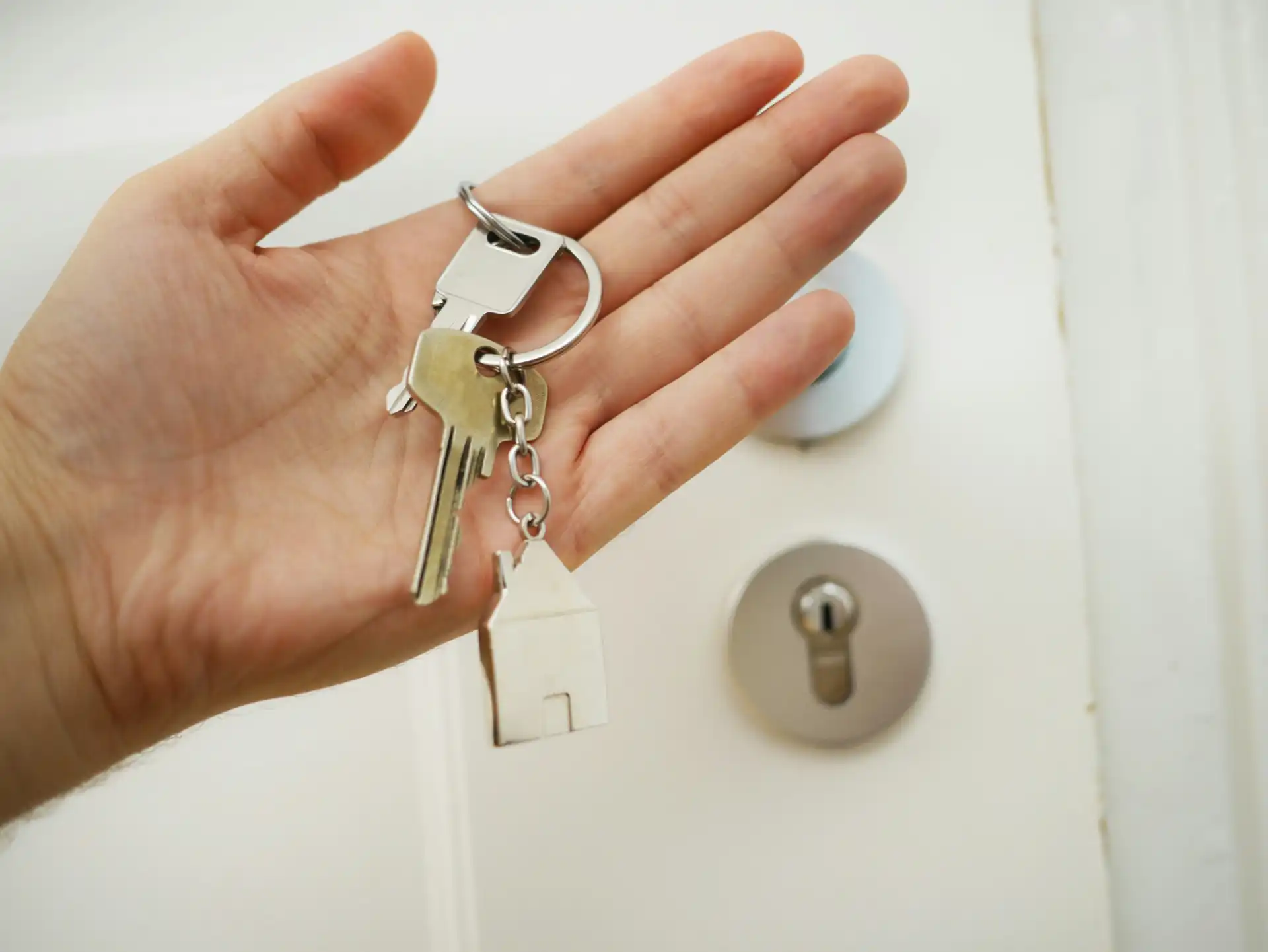 Pessoa segurando chave de casa com maçaneta na porta, simbolizando negociação imobiliária. Vídeo ilustrativo para quem busca tudo que precisa antes de escolher uma imobiliária.