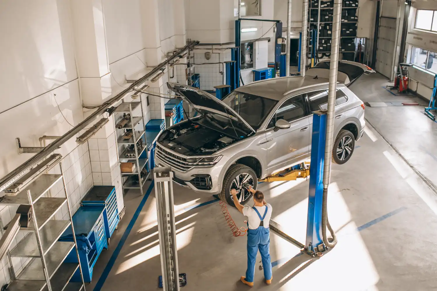 Imagem de um mecânico trabalhando em um carro em uma oficina moderna, destacando a laje treliçada em oficinas e centros automotivos.